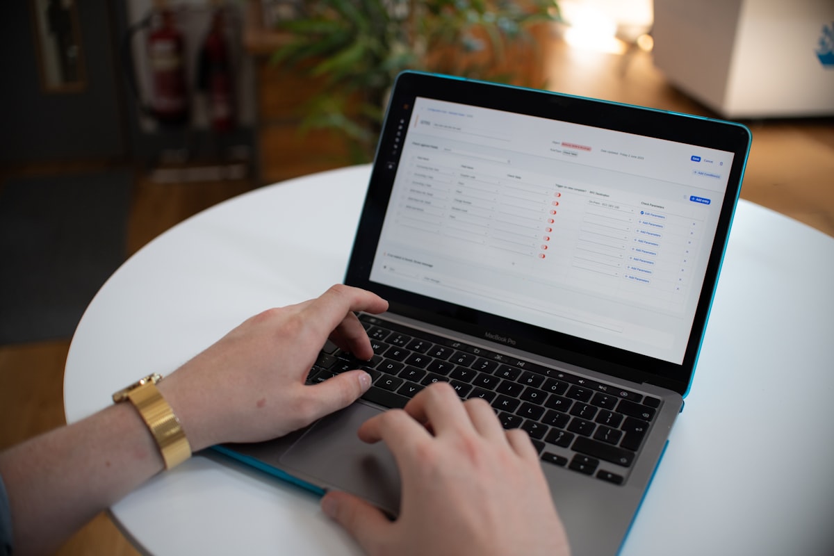 Mãos digitando num laptop com planilha de dados na tela