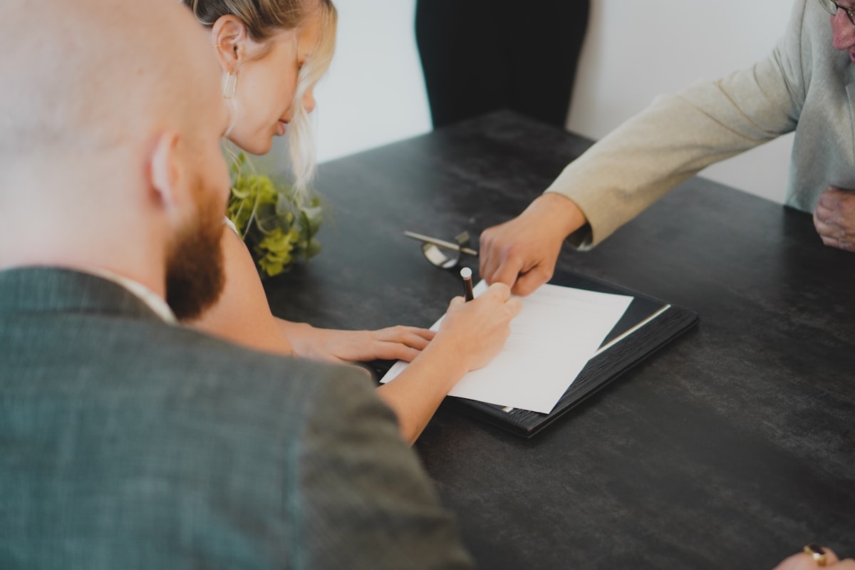 Duas pessoas assinando um documento numa mesa de reunião
